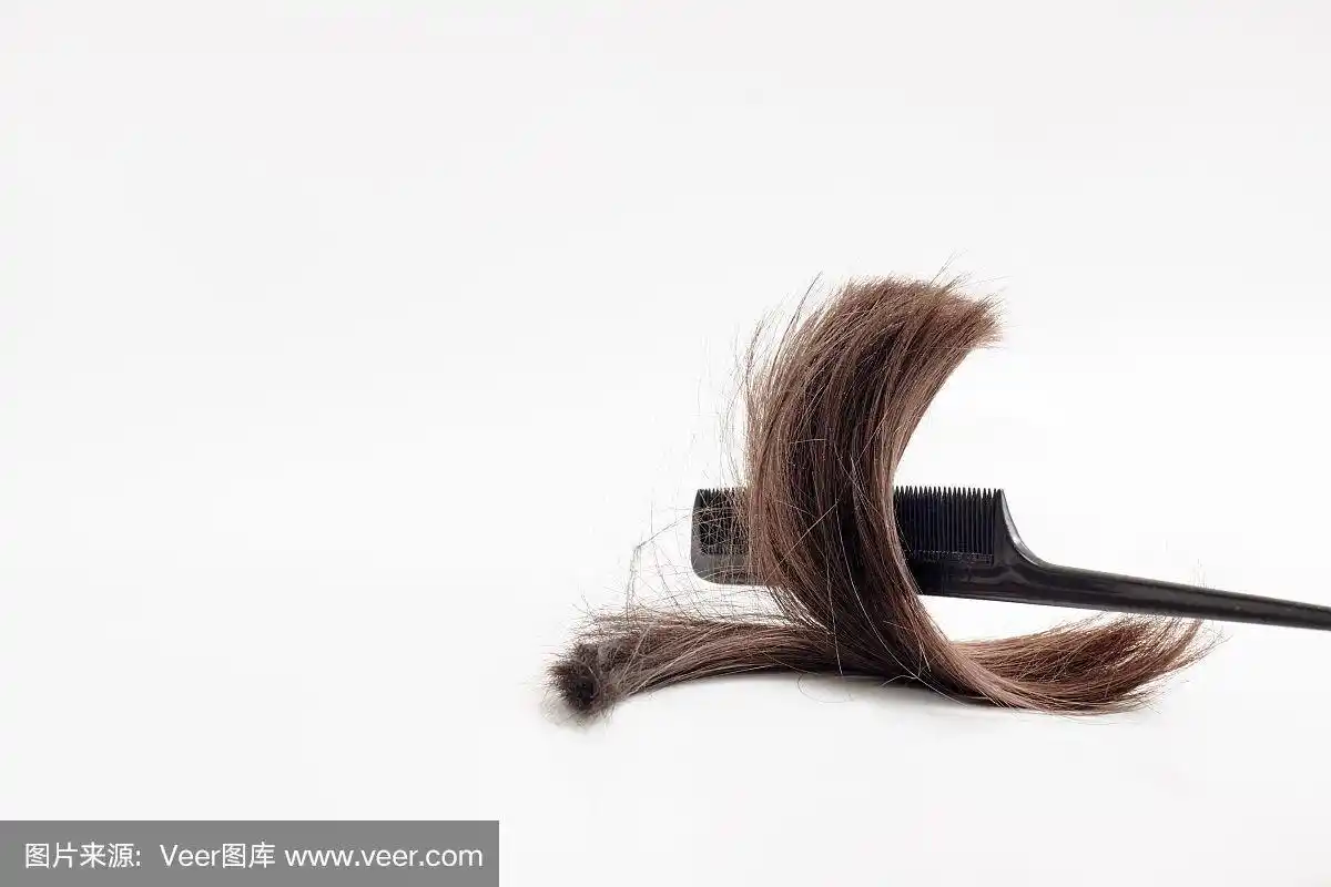 一绺棕色的头发和一把梳子放在浅白色的背景上.