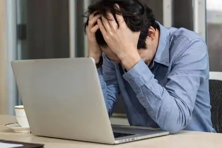 商务男士坐在办公室办公桌前压力很大照片