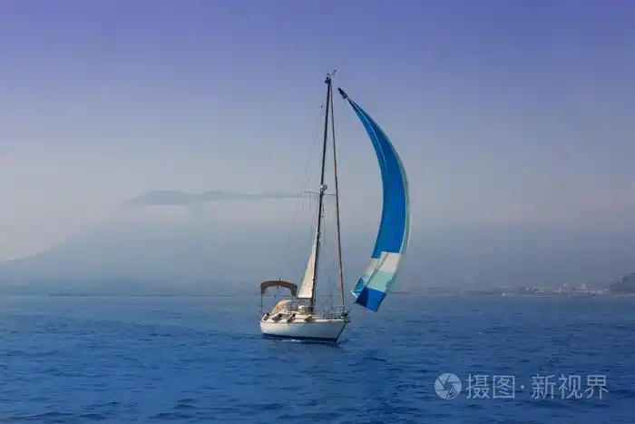 蓝色的大海与在有雾的海岸航行的帆船