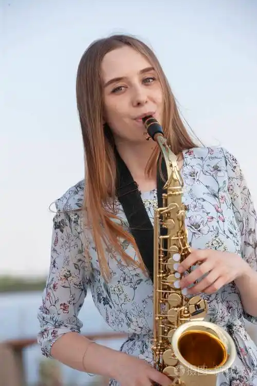 美丽的黑发女子在公园里吹萨克斯管