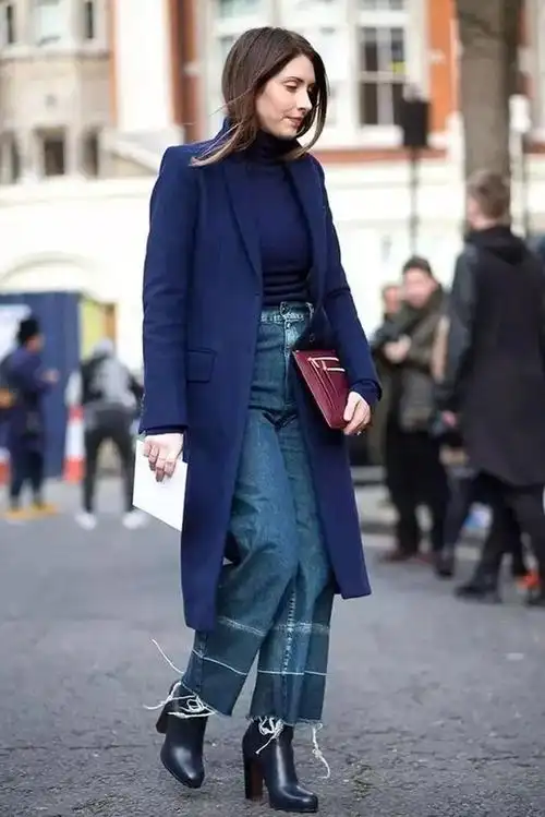图中的时髦精,上身穿着一件藏蓝色的中长款大衣,内搭一件同色打底衫