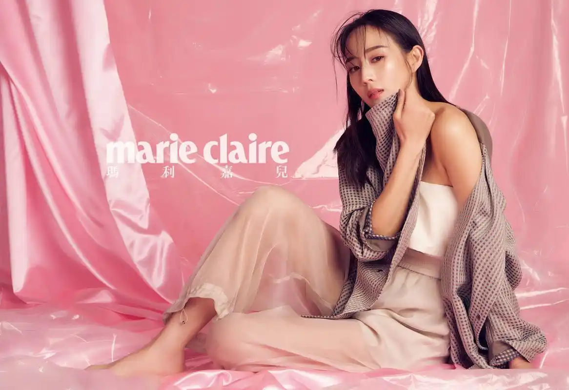 照片中张钧甯身处亮粉色背景中央,身穿藕荷色吊带装,头发微湿轻搭在肩