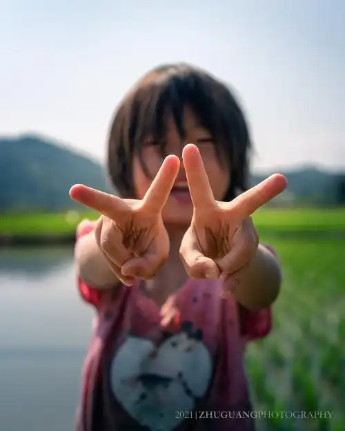 田野守望童真微笑不经意的瞬间拍下了女孩双手比耶的照片正好对焦在了