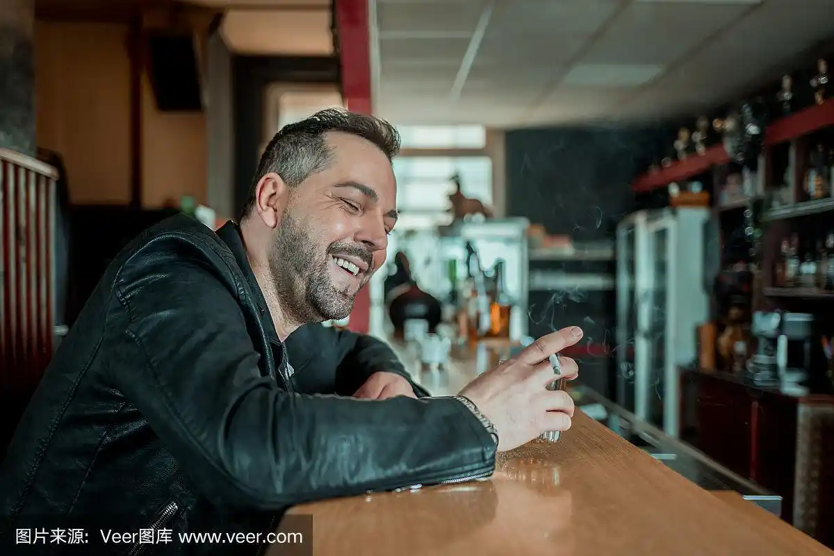 酒吧里一个手里拿着烟和酒,笑着的男人