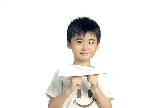握住纸飞机面带微笑的小男孩