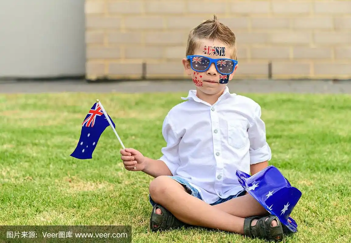 在澳大利亚日那天,可爱的男孩拿着澳大利亚国旗坐在前院