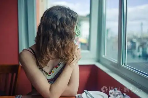 一个年轻的女人坐在餐馆的窗边