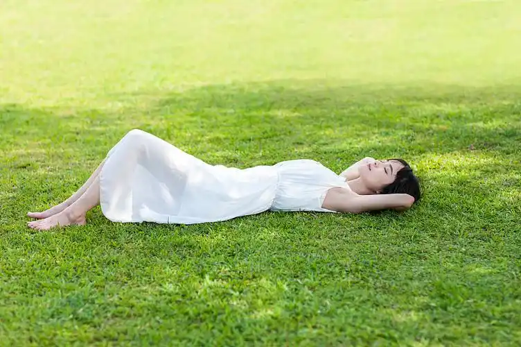年轻女人躺在草地上睡觉图片下载