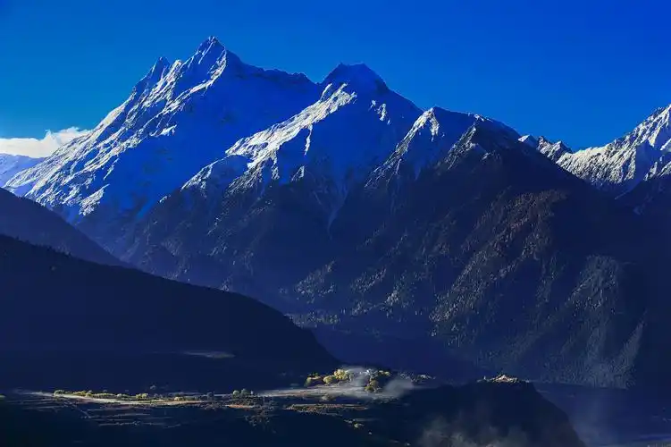 南迦巴瓦右侧的多雄拉雪山脚下,炊烟环绕在村子里的小屋间.