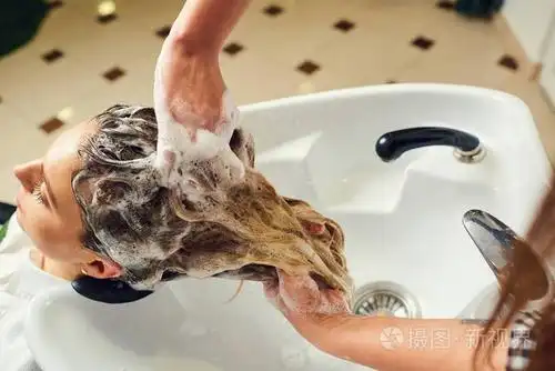 一个理发师女人洗到客户端的头发头坐在椅子上