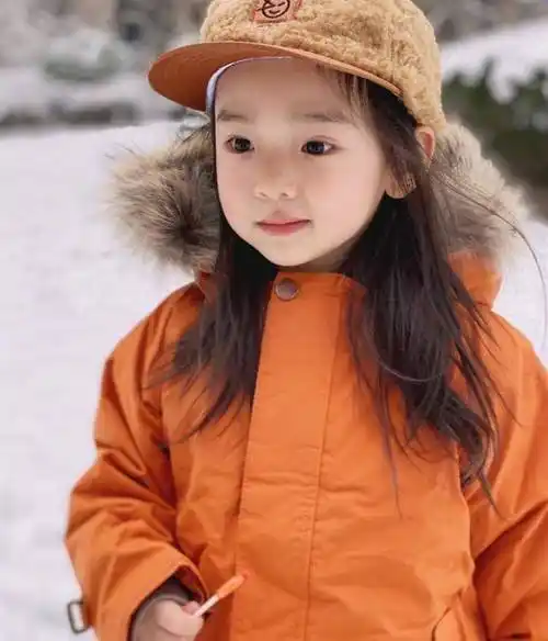 董璇女儿终于肯笑了穿橘色小袄配洋帽玩雪手拿棒棒糖脸型像爸