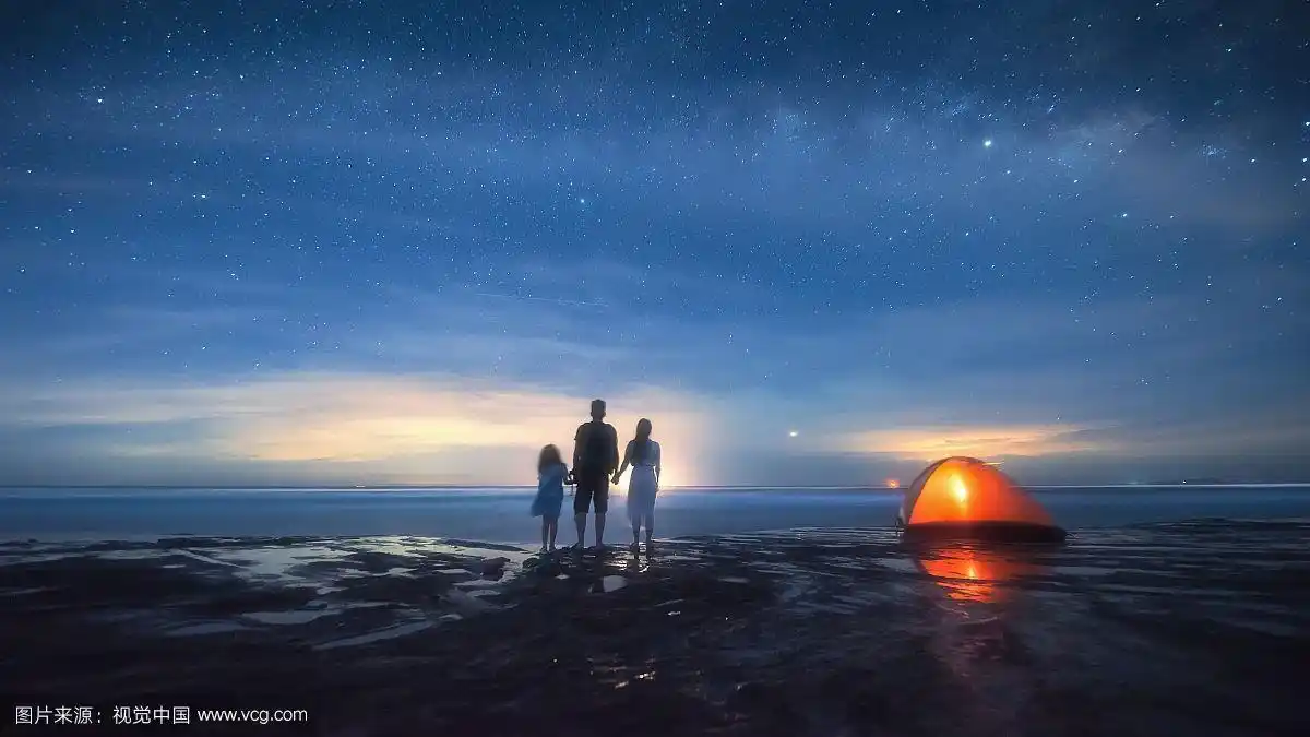 在广西的海边看日落的一家三口
