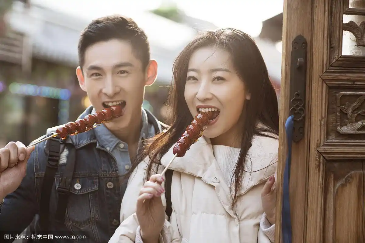 快乐的情侣在游玩吃冰糖葫芦