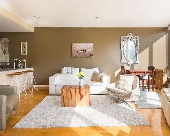 浅棕的墙面和暖棕的地面共同营造了一个温馨的客厅空间,阳光洒进,躺在