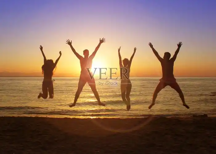 一群快乐的年轻人在海滩上蹦蹦跳跳照片摄影图片