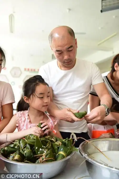 5月29日,山东烟台龙海小学的小学生和家长一起包粽子.