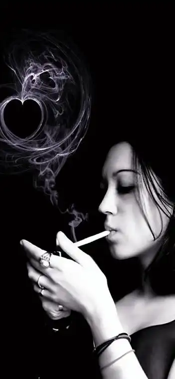 穿着灰黑色的卫衣外套嘴巴叼着烟一个手挡风一个手拿着打火机准备点烟