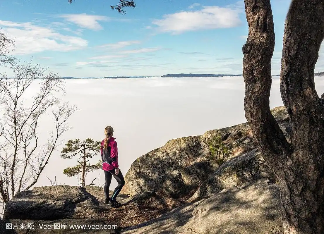 一个女人站在山顶上望着下面的大海