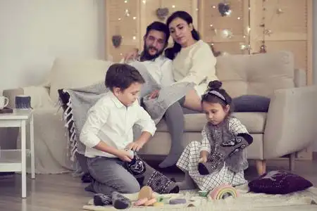 孩子们兄妹在地板上一起画画,年轻的父母则在沙发上放松照片