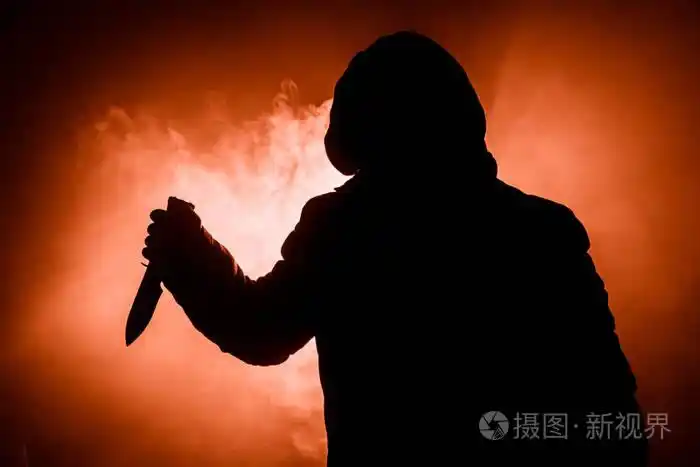 一个危险的蒙面人站在黑暗中拿着一把刀. 脸是看不见的. 实施犯罪概念