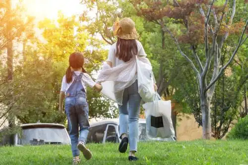 小女孩和妈妈手拉手走在草地上的背影