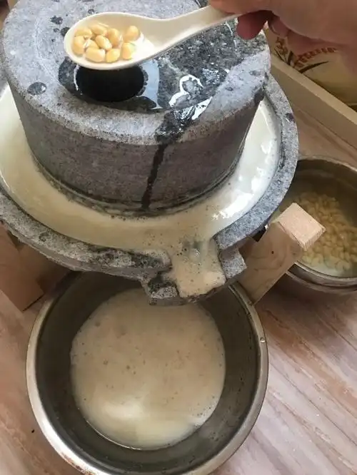 黄豆加入水,用石磨开始磨豆浆