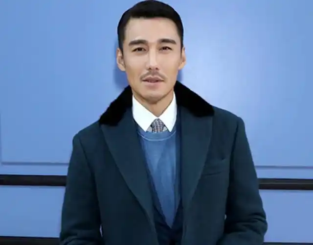 胡兵身穿蓝色大衣,时尚儒雅.