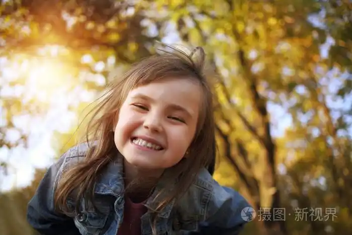 在阳光明媚的公园欢乐的年轻女孩微笑