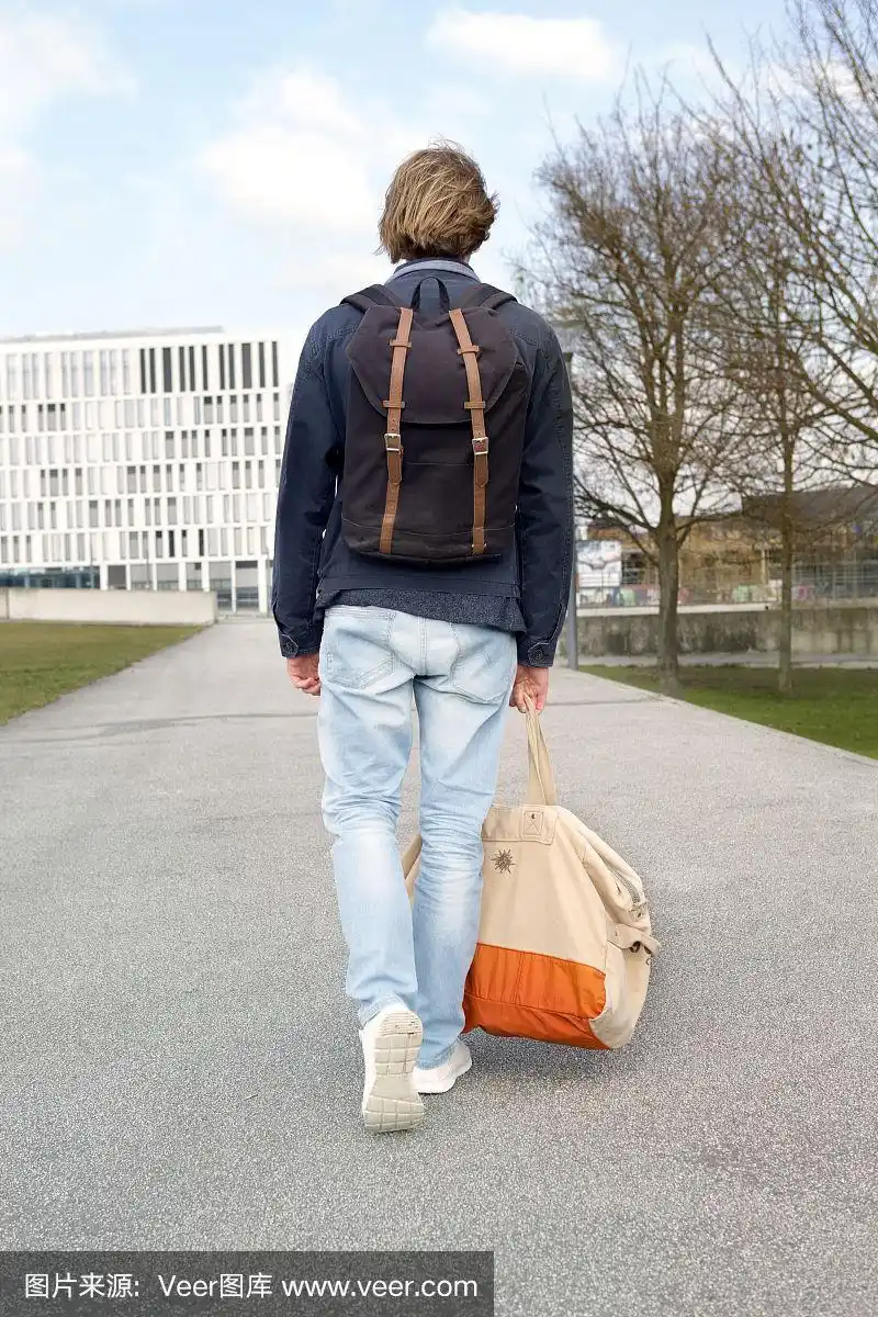 一个背着包走在街上的年轻人的背影