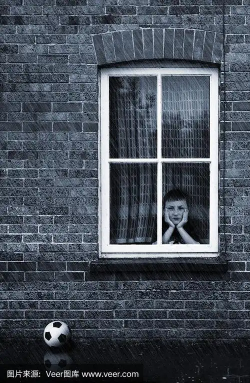 悲伤的小男孩盯着窗外在雨天