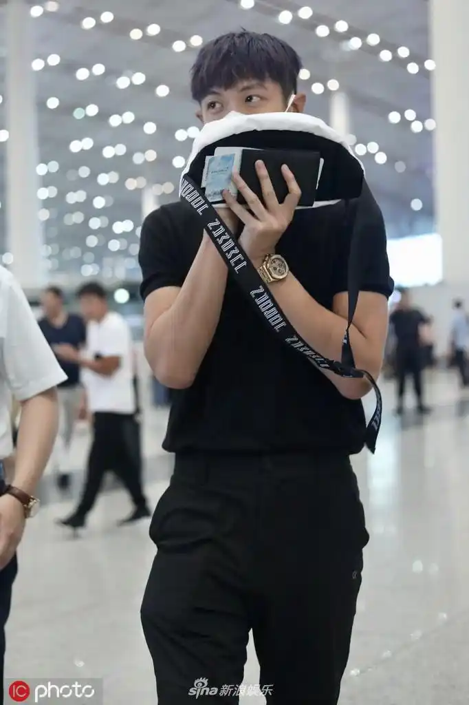组图柯震东现身机场用包挡脸换新发型肤色黑不少