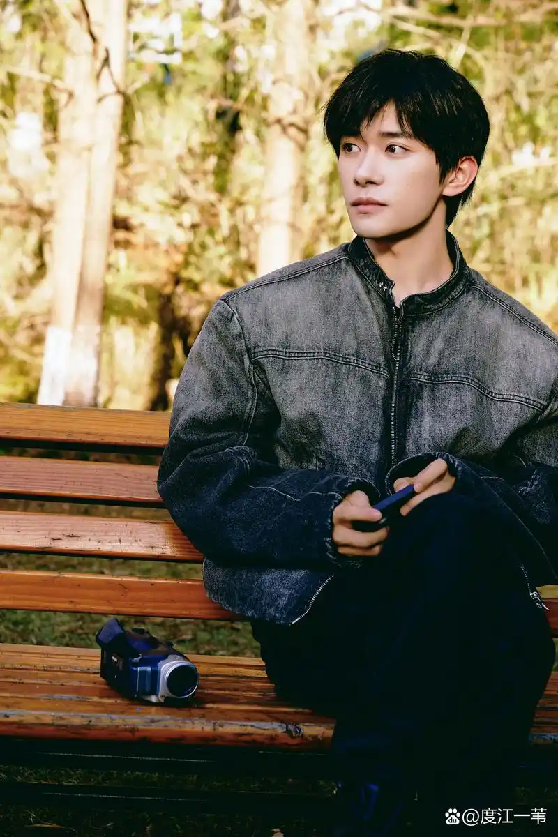 易烊千玺,身穿牛仔衣,静静地坐在那里,微笑着凝视着镜头.