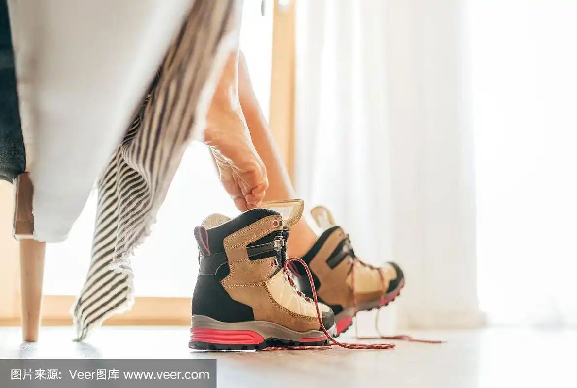 年轻性感的赤足女性穿上新的徒步靴与解开的鞋带下在明亮的阳光下的坏