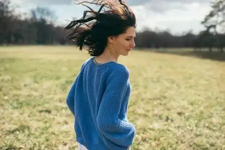 安静享受背面的美丽年轻的黑发妇女与风吹头发的自然背景.