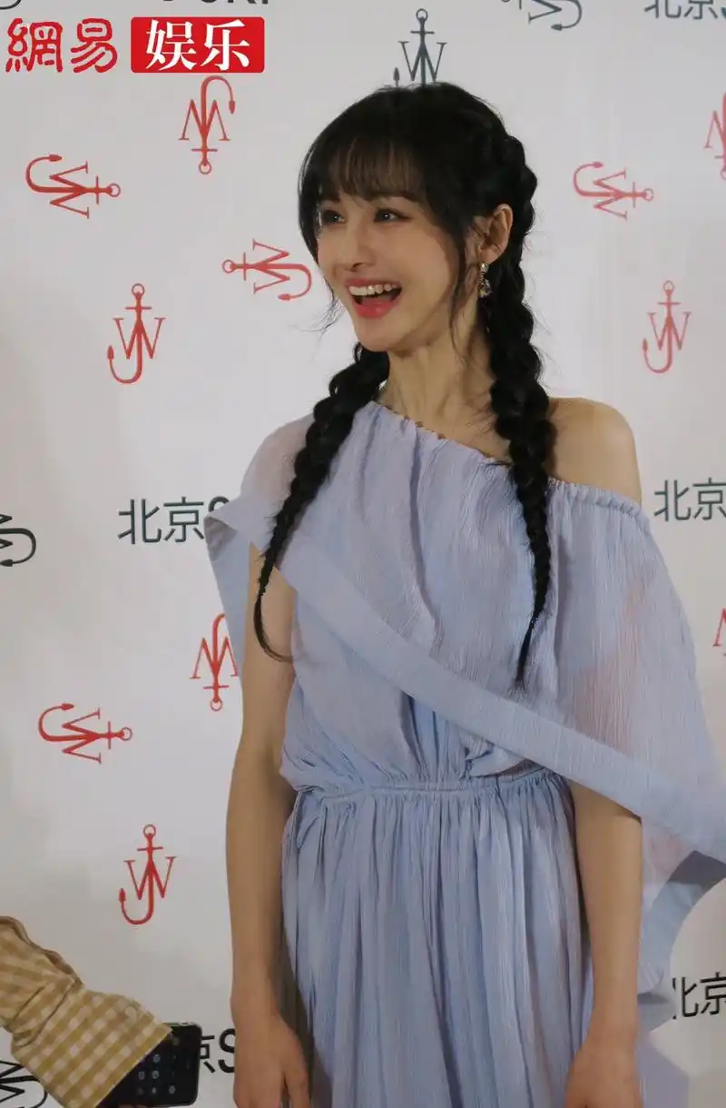 郑爽身穿一袭蓝色纱裙搭配麻花辫亮相某时尚活动,表情俏皮可爱,是吃糖