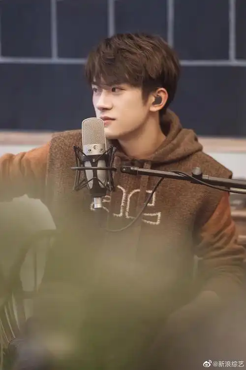 易烊千玺穿复古连帽马甲专注聆听梨涡浅笑文艺范十足