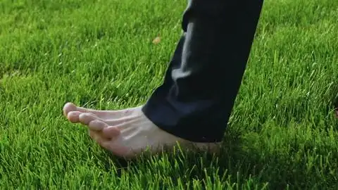 西装男赤脚走在草坪上上班族下班后放松特写