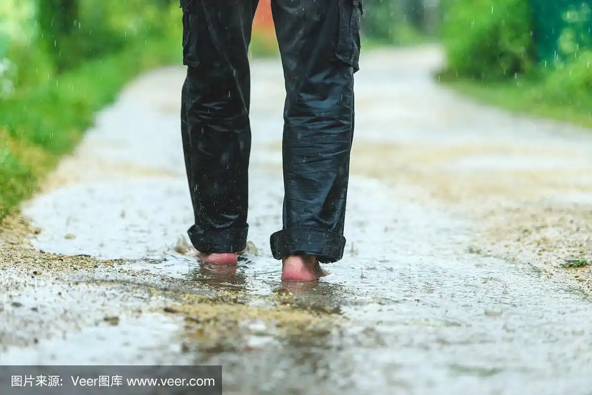 一个男人在雨中赤脚在水坑里