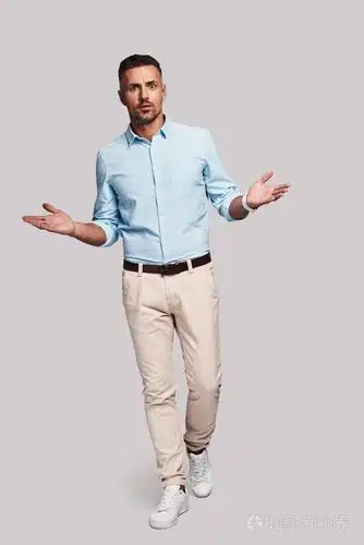 在灰色背景下行走时,一个惊讶的年轻人盯着他,双臂张开