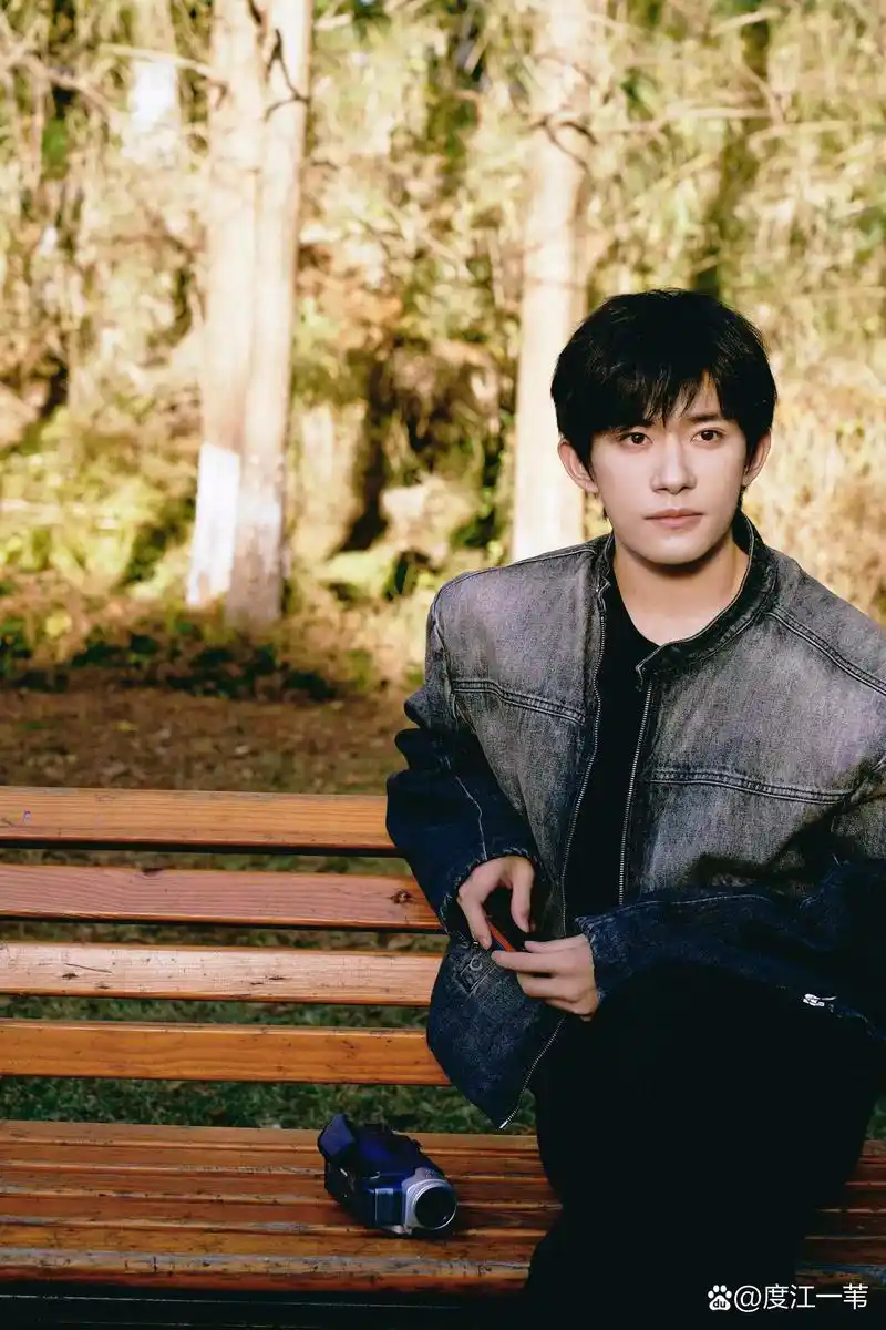 易烊千玺,身穿牛仔衣,静静地坐在那里,微笑着凝视着镜头.