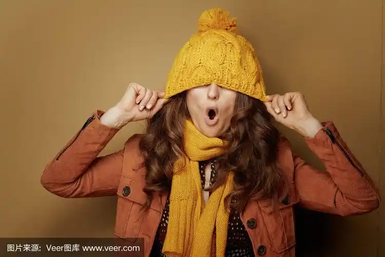 开朗时尚的女人与贝雷帽在棕色的背景上的眼睛