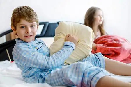 学前班和小学生在一起玩得很开心.孩子们在床上一起玩耍.做枕头大战.