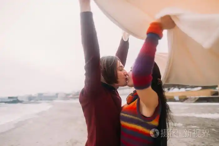 有魅力的年轻幸福夫妇在白色的毯子里接吻