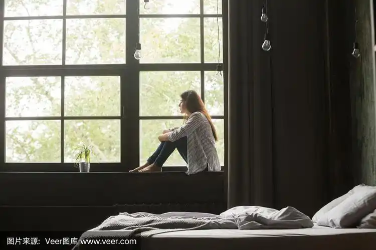 孤独悲伤的年轻女子坐在家里的窗台上