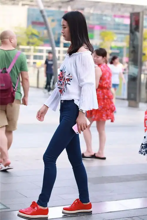 路人街拍穿着红色运动鞋的紧身牛仔裤美女身材比例十分匀称