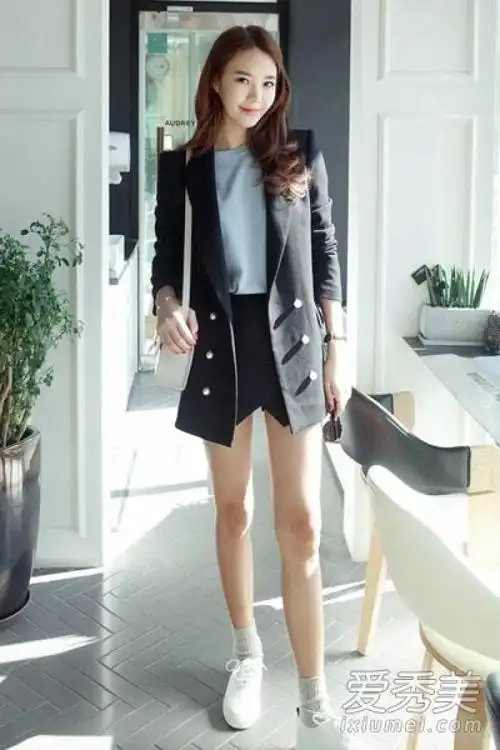 黑色小西装简洁修身,搭配浅蓝色t恤衫和黑色短裤,脚踩一双白色休闲鞋