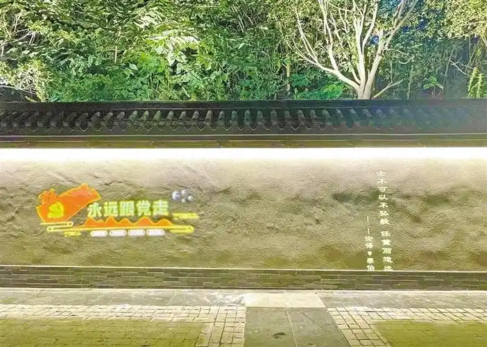 图为被照射在遗址公园外墙上的"永远跟党走"标识.