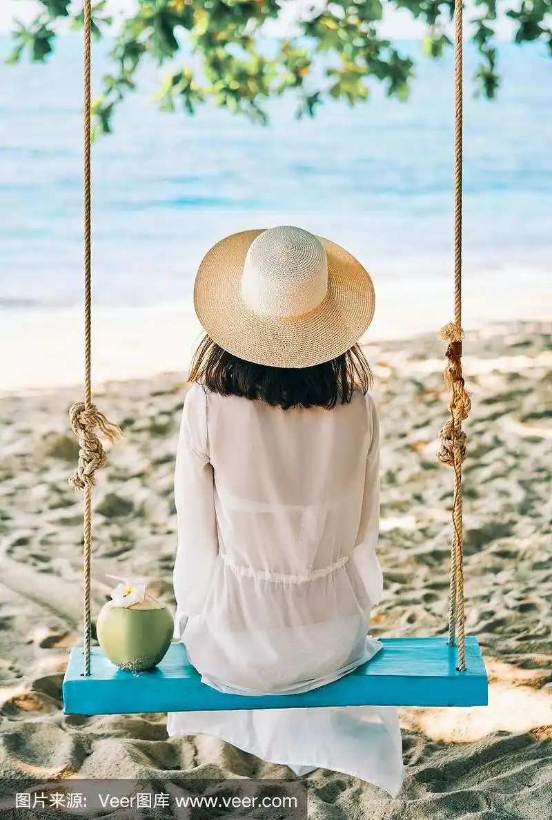 快乐的女人在美丽的天堂海滩上荡秋千放松的背影