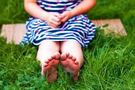 在绿色的草地上脚在绿色草地上的小女孩的脚的特写照片