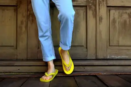 女人的腿和脚,穿着黄色凉鞋站在木地板和木墙背景,非常适合任何用 ..